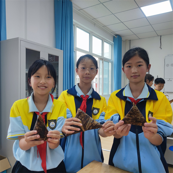 洋县书院小学学生展示她们包的粽子.jpg