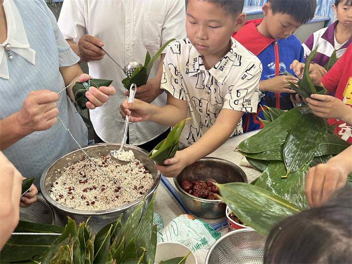 学生在家长的指导下制作粽子.jpg 学生在家长的指导下制作粽子.jpg